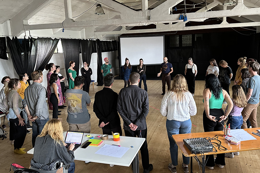 Group of people in a circle working in a big room.