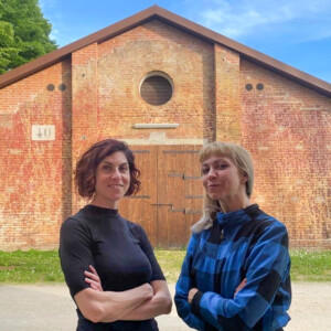 Two women standing in front of a red-brick building.